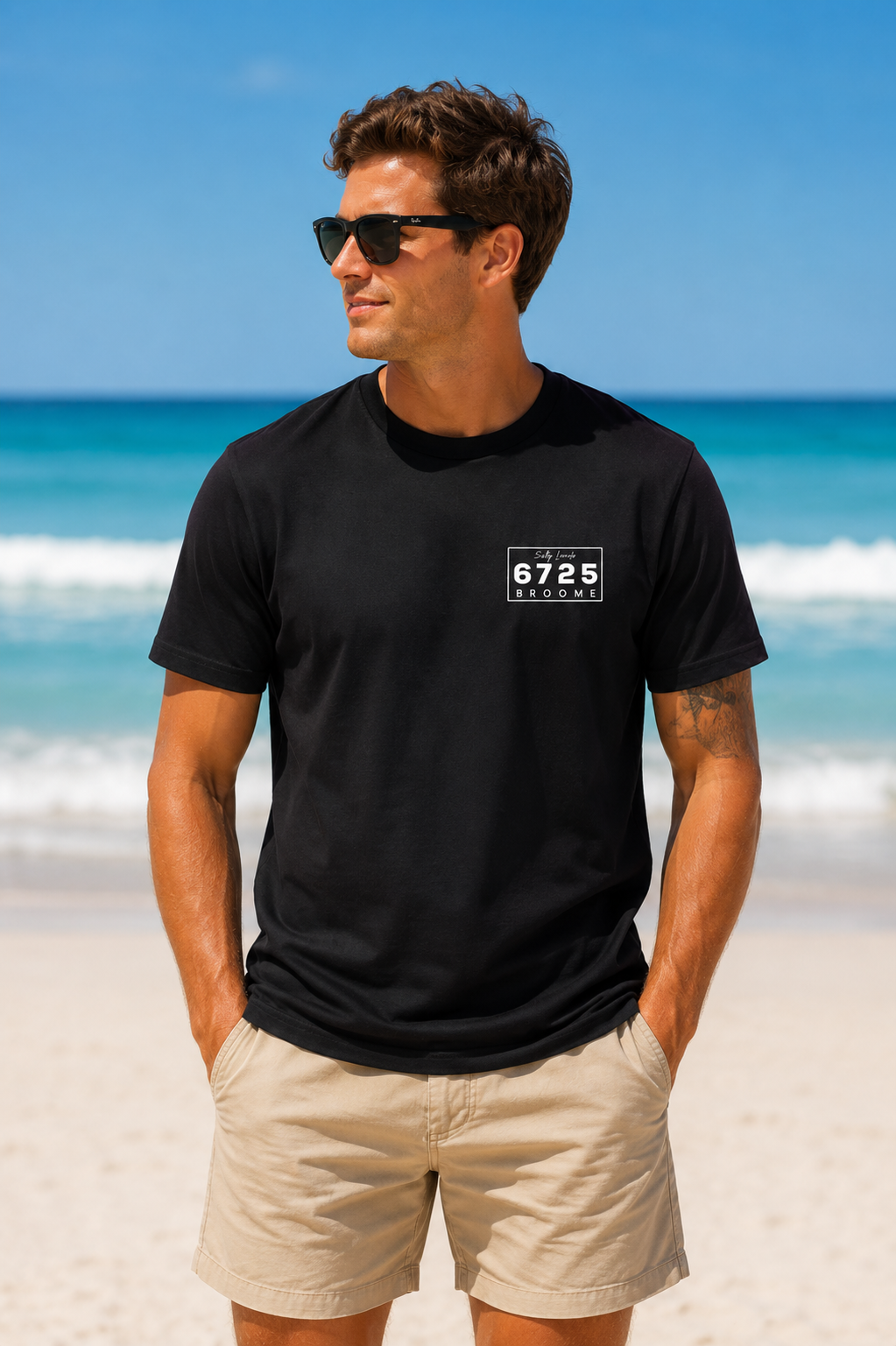 Men's "Salty Locals" Shark T-Shirt - Black | 6725 Broome worn by a model at the beach, showcasing style and comfort.